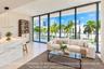 Floor-to-ceiling glass wall, expansive private balcony, stone-finish kitchen island with waterfall edge, built-in cabinetry, and large-format tile flo
