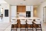 Kitchen featuring an expansive center island with a stone-finish countertop, integrated built-in appliances, flat-panel cabinetry in white and natural