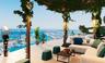 Expansive terrace featuring a wood-beam pergola, glass perimeter railing, and integrated wall-mounted lighting