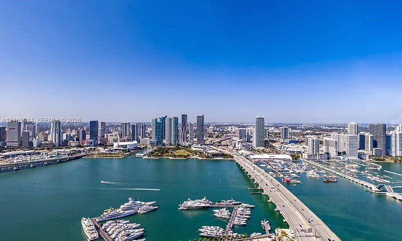 Aerial perspective capturing a cityscape, expansive waterfront, causeway, and multiple deep-water marinas