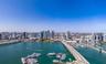 Aerial perspective capturing a cityscape, expansive waterfront, causeway, and multiple deep-water marinas