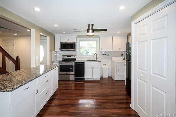 Kitchen with white cabinetry, black appliances, dark wood finished floors, washer / clothes dryer, and recessed lighting