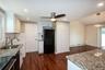 Kitchen with light stone countertops, white cabinets, tasteful backsplash, black appliances, and dark wood-style floors
