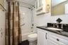 Bathroom with shower / bath combo, tile walls, vanity, dark tile patterned flooring, and decorative backsplash