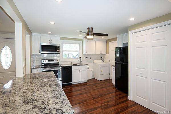 Kitchen featuring black appliances, white cabinetry, washer / dryer, dark wood-style flooring, and recessed lighting