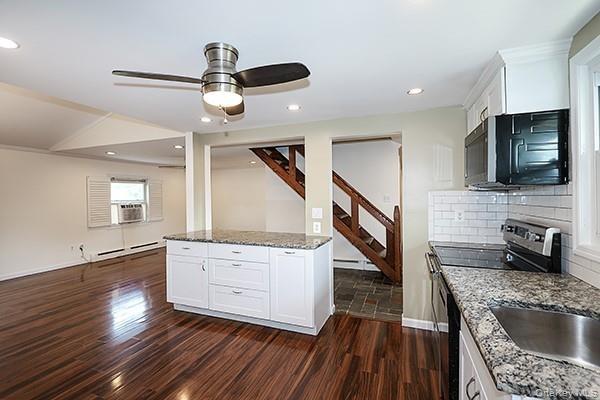Kitchen featuring stainless steel appliances, white cabinetry, dark stone countertops, dark wood-type flooring, and recessed lighting