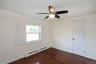 Empty room featuring crown molding, a baseboard heating unit, dark wood-style flooring, and a ceiling fan