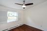 Empty room with a baseboard radiator, ornamental molding, dark wood-style floors, and a ceiling fan