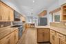 Kitchen featuring light-finish cabinetry, stone countertops, stainless steel gas range with a matching range hood, and wood-finish flooring