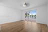 Interior space featuring wood-finish flooring, crown molding, a central ceiling fan with multi-light fixture, and sliding glass doors with access to a