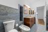 Dual-sink wooden vanity with stone countertop, built-in wall shelving, mosaic tile wall accents, and ceramic bidet