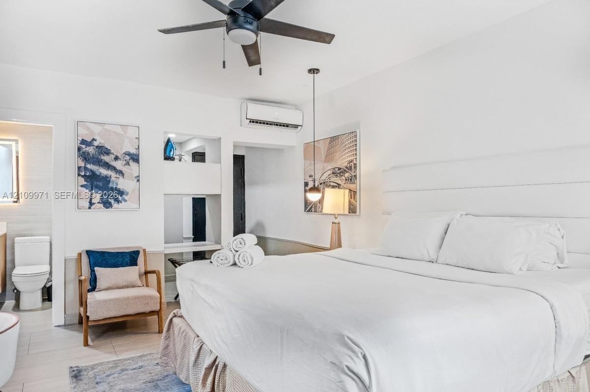 Neutral-toned interior featuring a recessed wall niche with built-in shelving, a modern ceiling fan, a wall-mounted ductless air conditioning unit, an