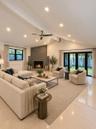 AI enhanced. Vaulted ceiling featuring recessed lighting, stacked-stone fireplace with a raised hearth, multi-panel glass doors, and polished stone fl