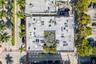 Aerial perspective of a commercial structure featuring a central courtyard with mature landscaping, a flat roof, and paved street-level parking
