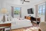 Room featuring wood-finish flooring, dual windows with muntin detailing, and a ceiling fan with integrated lighting