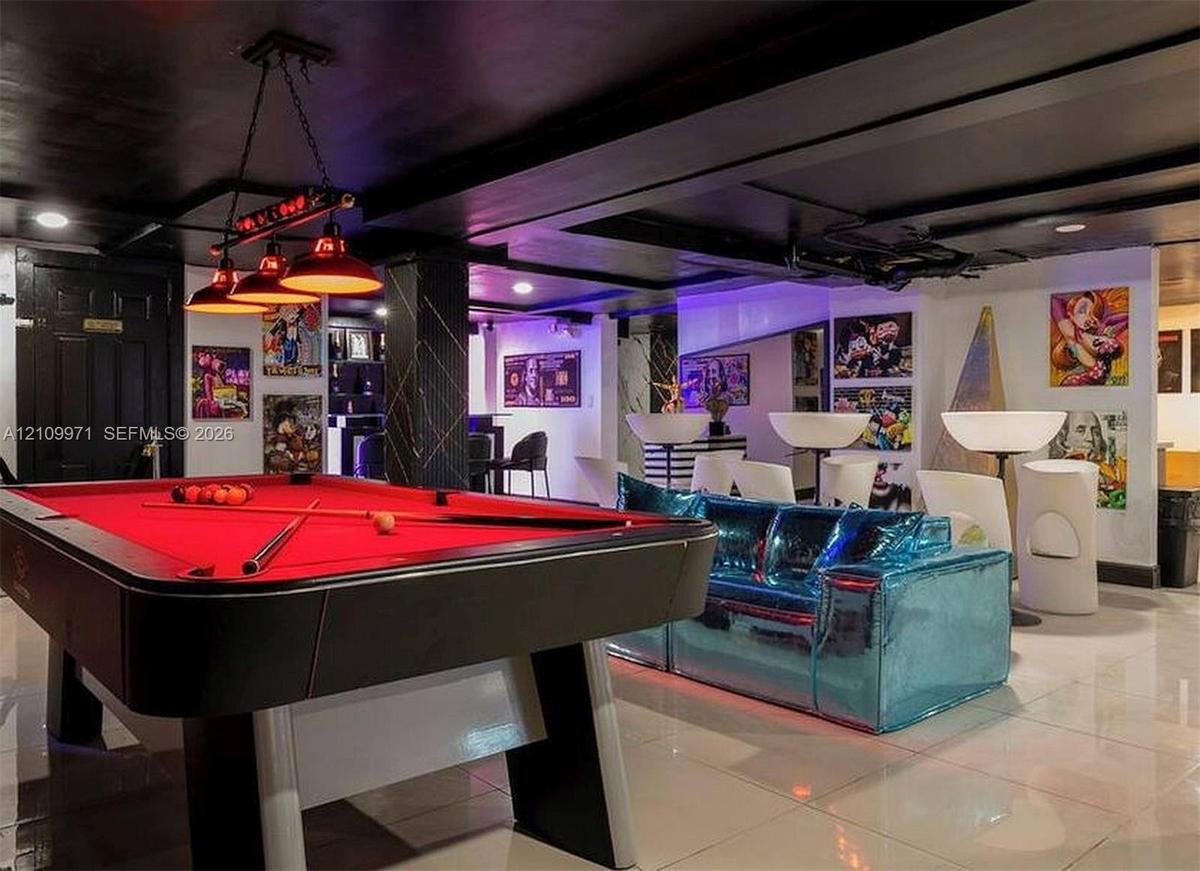 Interior space featuring a dark-toned exposed beam ceiling, glossy floor tiles, a structural pillar with decorative accent trim, and a three-bulb indu