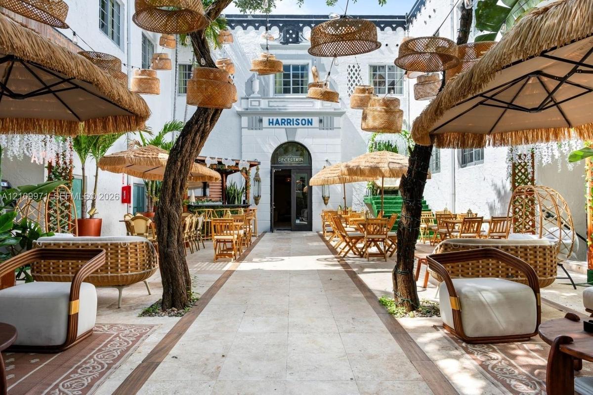 Open-air courtyard featuring stone tile paving, mature trees, built-in structural archways, and overhead decorative lighting