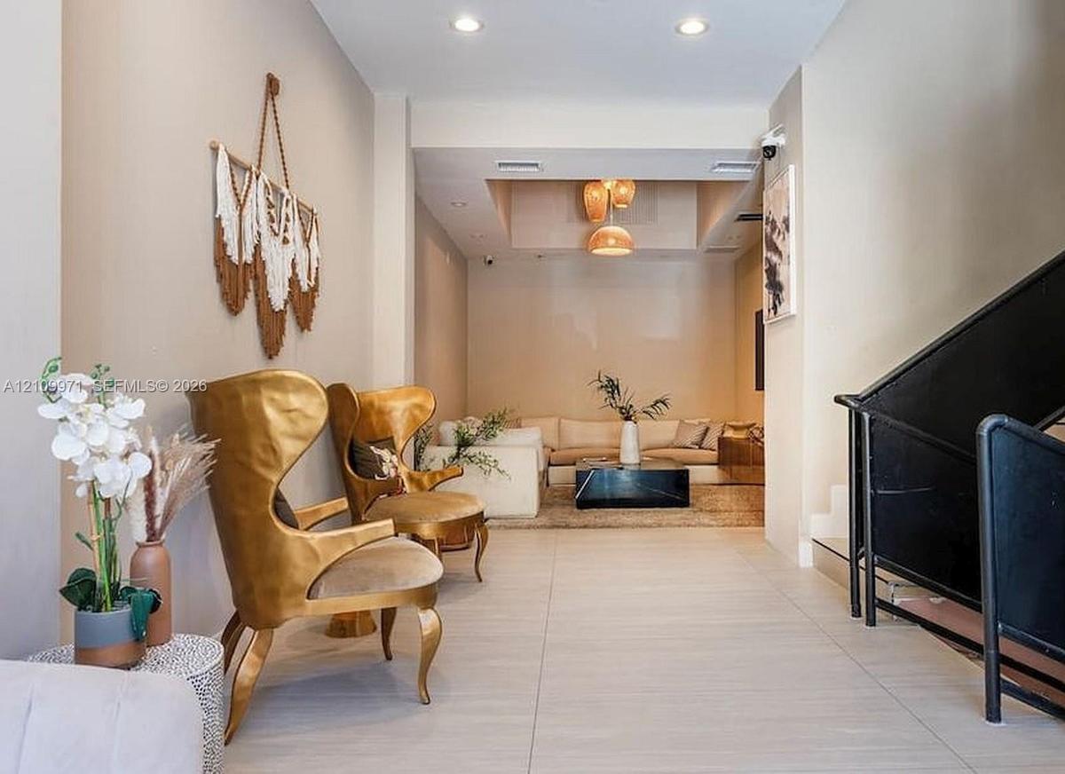 Neutral wall tones, large-format tile flooring, recessed ceiling lighting, multi-tiered pendant lighting, and an industrial-style staircase featuring 