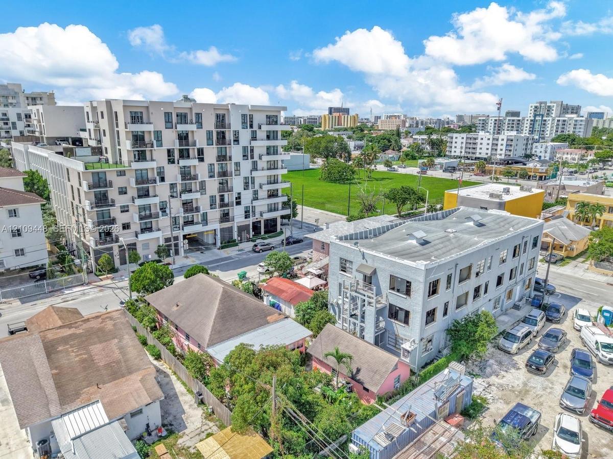 Aerial perspective of a multi-story urban residential building featuring a light-toned exterior facade, grid-pattern fenestration, and private balconi