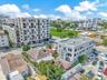 Aerial perspective of a multi-story urban residential building featuring a light-toned exterior facade, grid-pattern fenestration, and private balconi