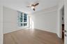 Neutral-toned interior featuring wide-plank wood-finish flooring, floor-to-ceiling windows, and a three-blade ceiling fan with an integrated light fix