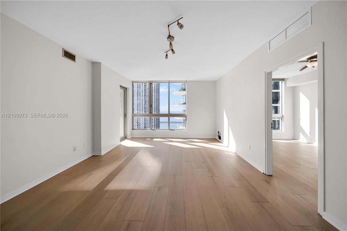 Open-concept living space featuring wood-finish flooring, floor-to-ceiling windows, and multi-directional track lighting