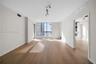 Open-concept living space featuring wood-finish flooring, floor-to-ceiling windows, and multi-directional track lighting
