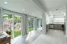 Kitchen featuring stainless steel appliances, white upper cabinetry, grey lower cabinetry, and recessed lighting, paired with floor-to-ceiling glass s