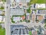 Aerial perspective featuring a multi-story residential structure, paved street access, and dense urban surroundings