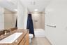Bathroom featuring a stone-look countertop, integrated sink, vanity cabinetry, and a tub-shower combination with tile surround