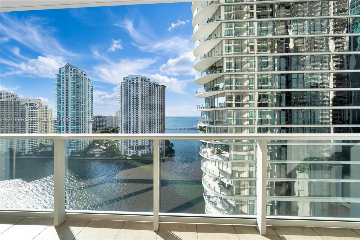 Private balcony featuring glass panel railing, tile flooring, and urban water scenery