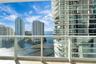 Private balcony featuring glass panel railing, tile flooring, and urban water scenery