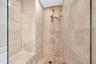 Walk-in shower featuring floor-to-ceiling stone tile, built-in stone bench, glass enclosure, and adjustable handheld shower fixture