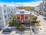 Two-story multi-family structure with a hipped roof, dormer window, masonry facade, and perimeter chain-link fencing