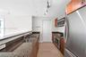 Kitchen featuring wood-finish cabinetry, stone countertops, stainless steel appliances, dual-basin sink, and track lighting