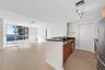 Open-concept living space featuring wood-finish flooring, floor-to-ceiling windows, natural stone kitchen countertops, and track lighting