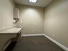 Built-in solid surface countertop with integrated sink, gooseneck faucet, upper wall-mounted cabinetry, and recessed drop ceiling