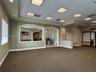Expansive interior featuring a recessed tray ceiling with integrated drop-tile panels, decorative arched wall cutouts, built-in shelving, and neutral 