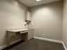 Built-in cabinetry with laminate countertop, integrated sink with faucet, wall-mounted upper storage cabinet, and carpeted flooring