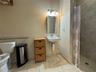 Bathroom featuring a wall-mounted sink with a chrome faucet, medicine cabinet with integrated lighting, tiled walk-in shower, and horizontal grab bar