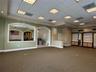 Expansive interior space featuring a drop ceiling with recessed lighting, integrated built-in cabinetry, dual arched wall cutouts, and a neutral color