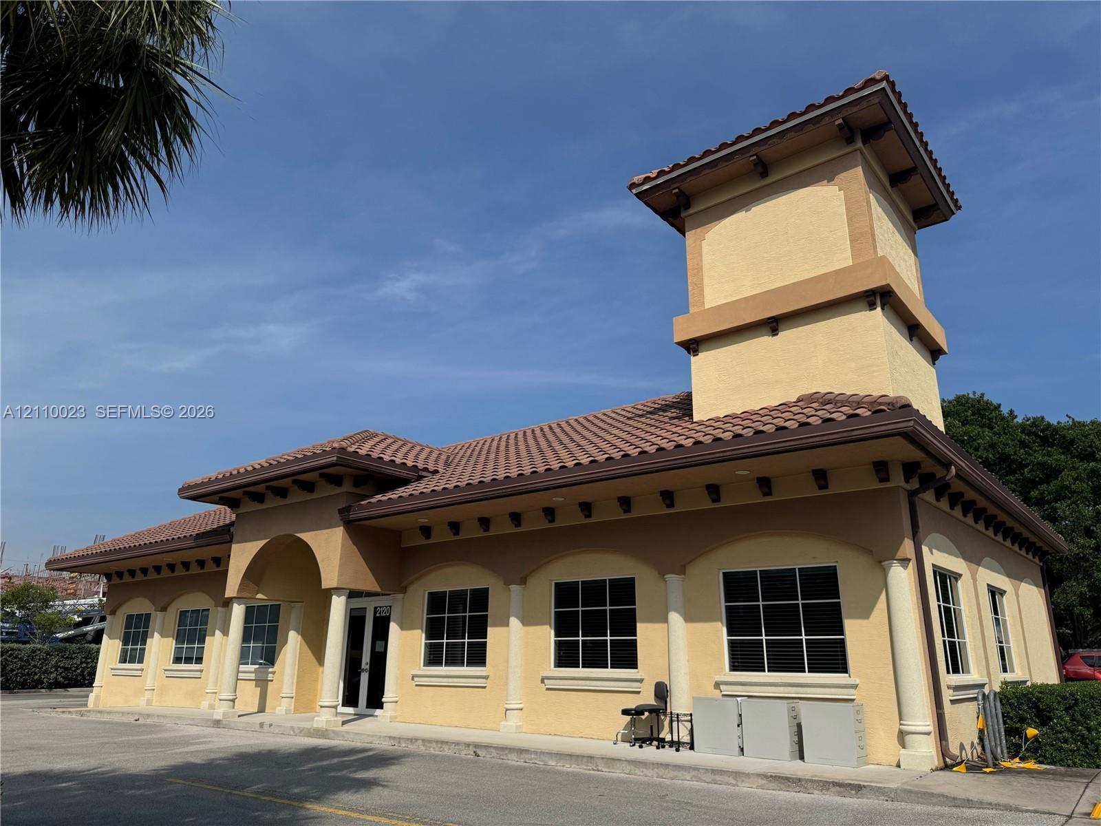 Stucco exterior featuring a prominent tower, mission-style tile roofing, decorative rafter tails, and a covered entry with column detailing