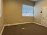 Neutral interior space featuring carpeted flooring, a large window with horizontal blinds, and a solid-core paneled door