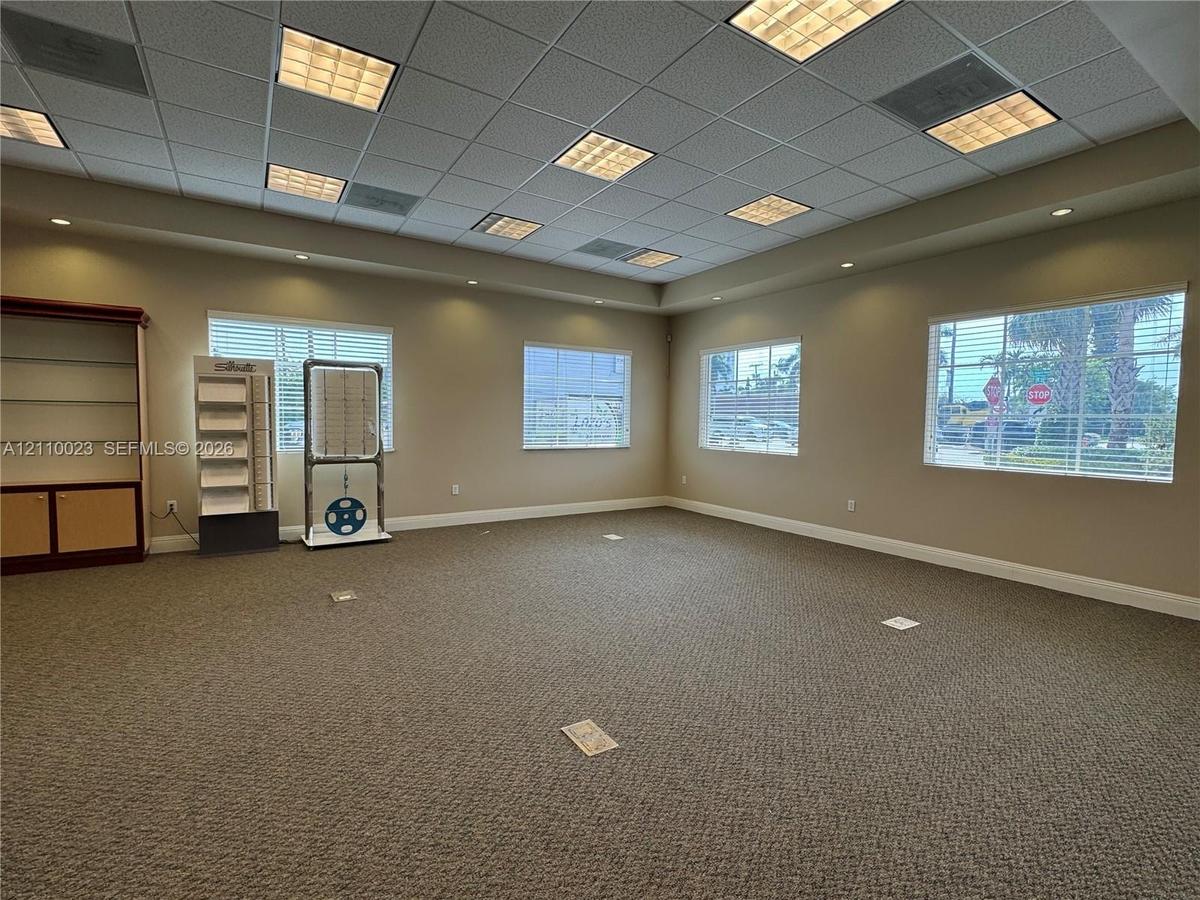 Spacious interior featuring a coffered grid ceiling with recessed panel lighting, neutral wall-to-wall carpeting, multiple windows, and built-in wood 