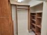 Custom wood-finish closet system featuring vertical shelving units, horizontal storage racks, and an integrated hanging rod