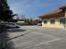 Paved parking area with concrete wheel stops, stucco exterior, clay tile roofing, and arched window frames