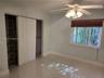 Large-format tile flooring, ceiling fan with integrated lighting, window with fitted blinds, and built-in closet shelving