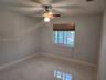Polished stone-finish flooring, ceiling-mounted light fixture with integrated fan, and sliding window with wood-slat blinds