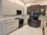 Kitchen featuring two-tone high-gloss cabinetry, stone-finish countertops, tile backsplash, stainless steel appliances, and large-format floor tiling