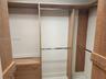 Custom wood-finish shelving unit featuring tiered hanging rods, built-in cabinetry, and integrated metal hooks